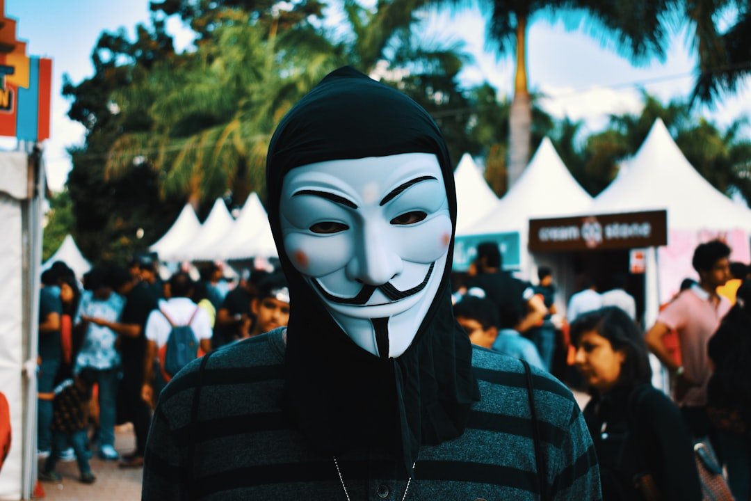 person wearing Guy Fawkes mask near people during day