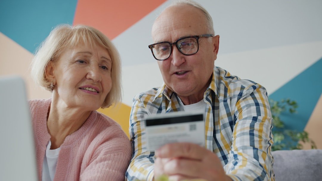 Elderly couple looking at credit card and laptop.