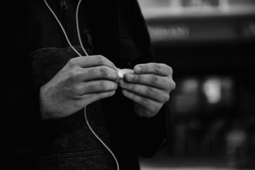 Person's hands untangling white earbuds