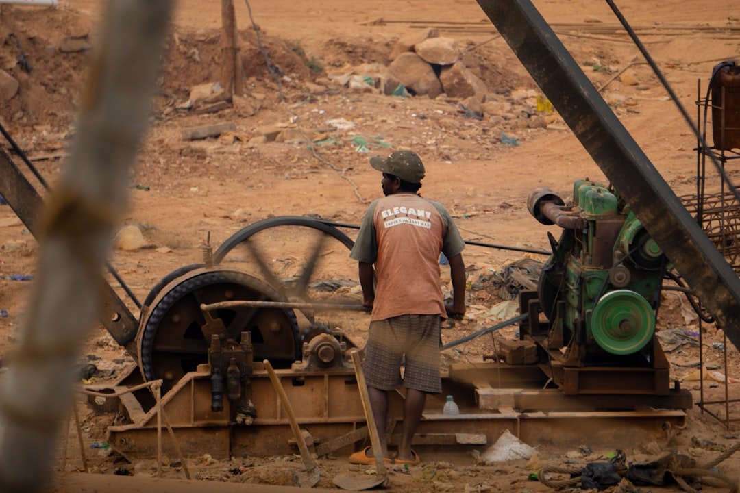 A man standing next to a machine in a dirt field