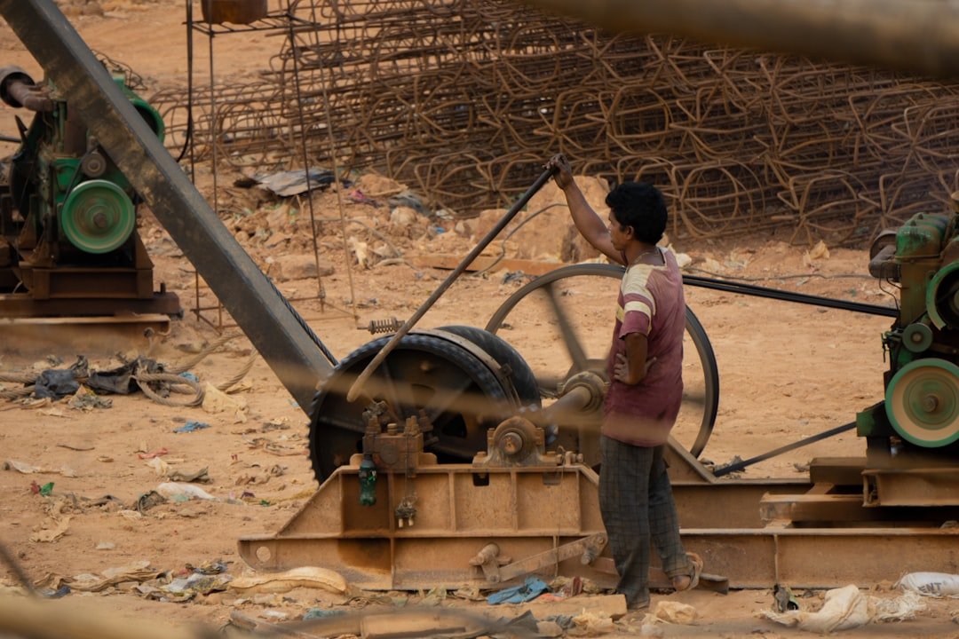A man standing next to a machine in a dirt field