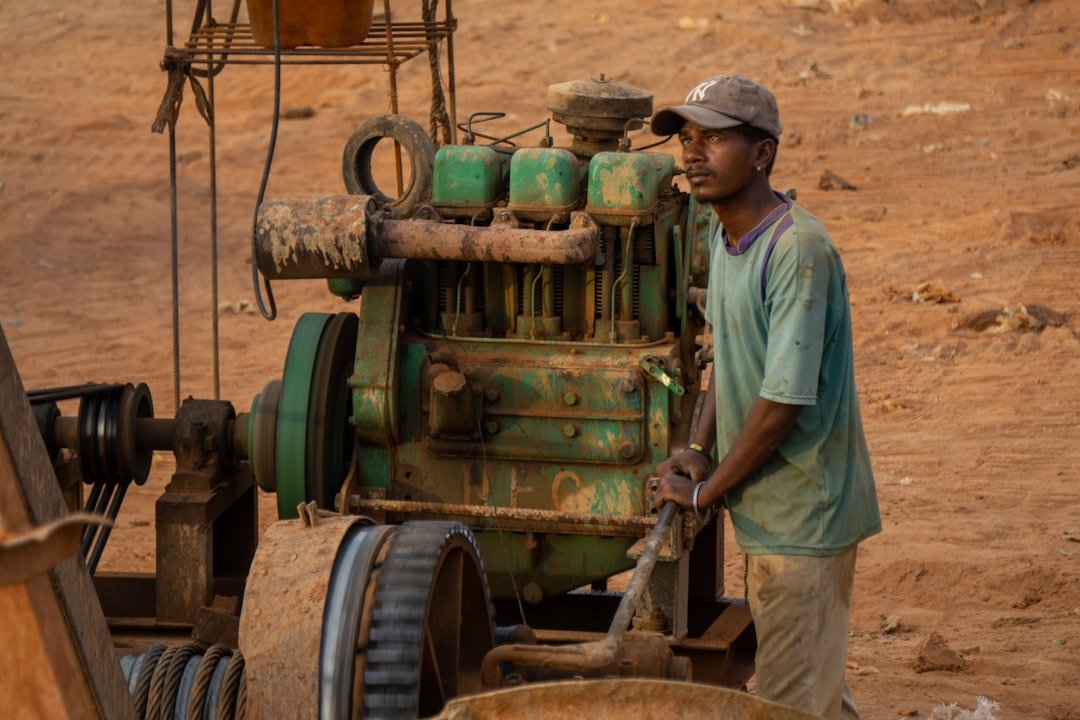 A man standing next to a machine in the dirt