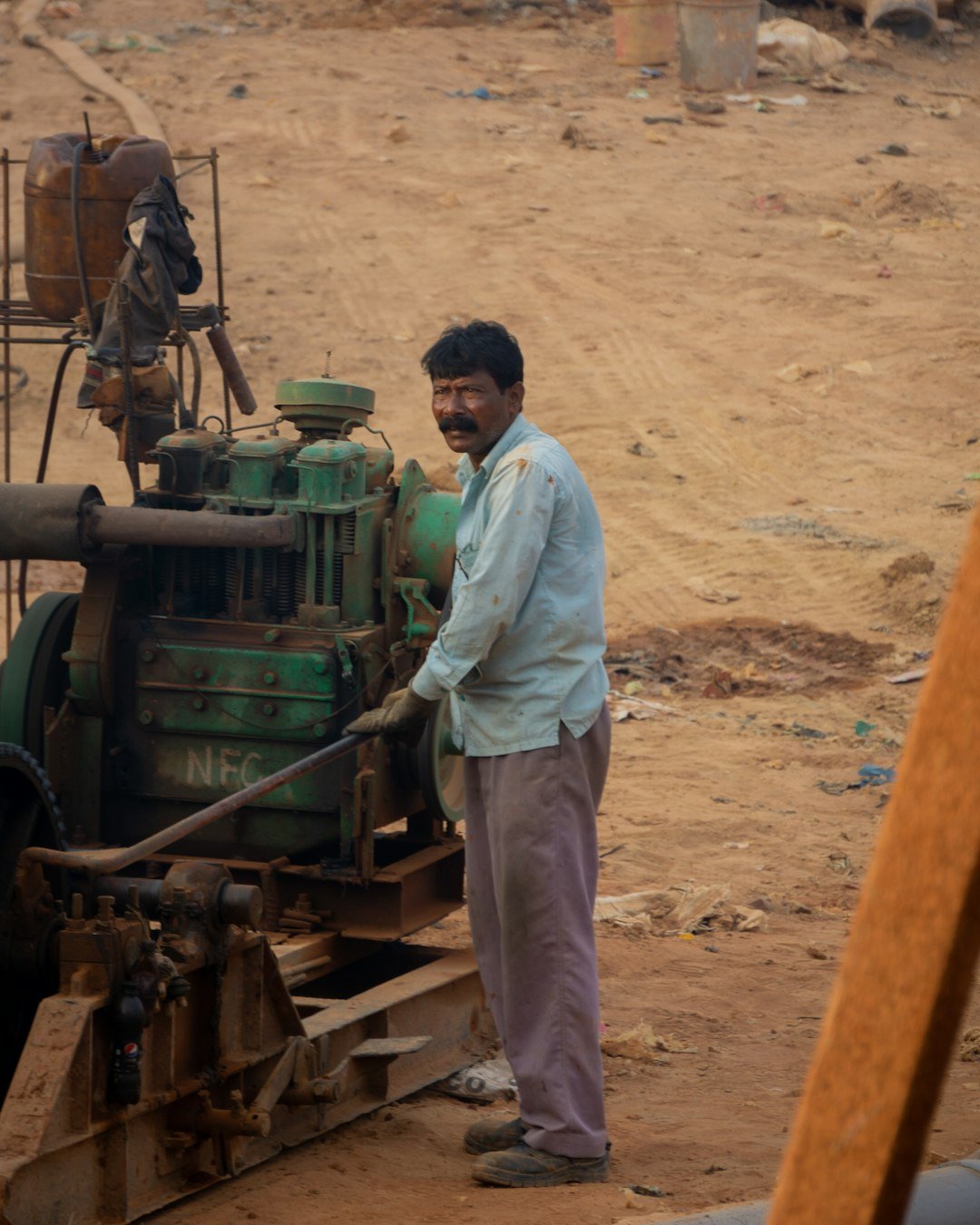A man standing next to a machine in the dirt