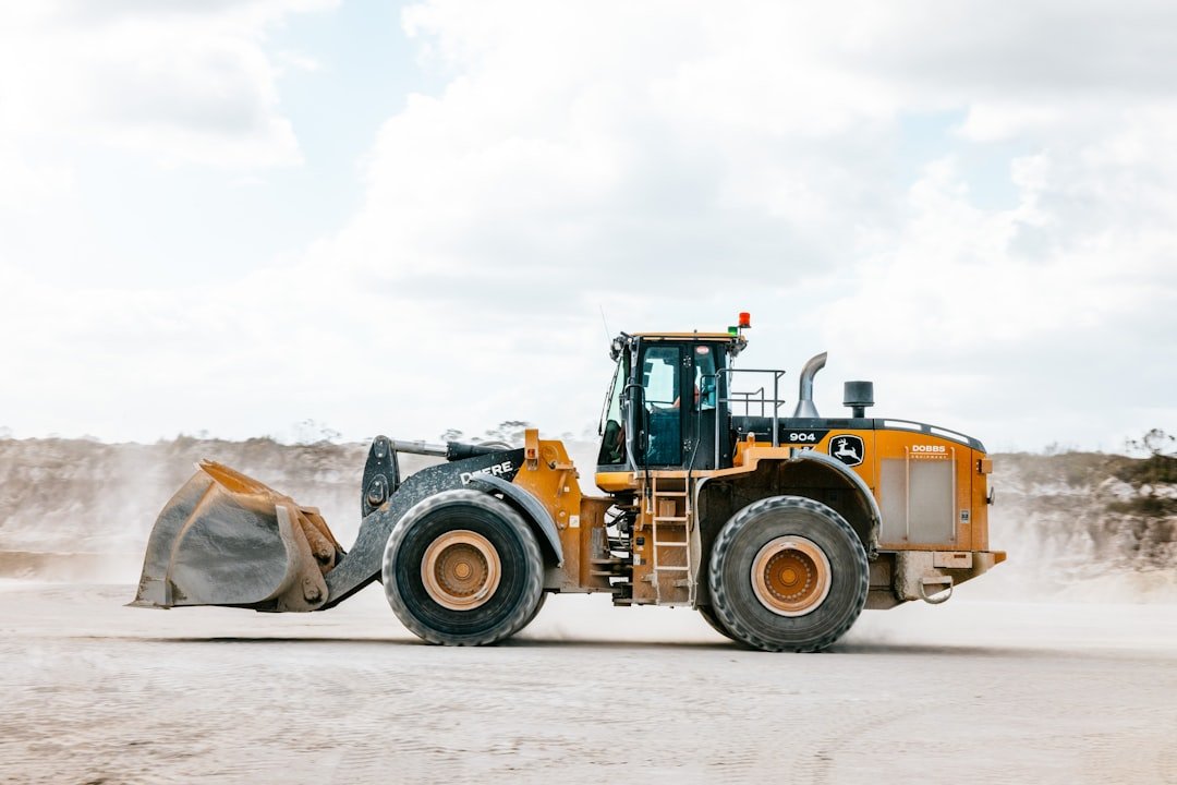 A large loader kicks up dust in the dirt.