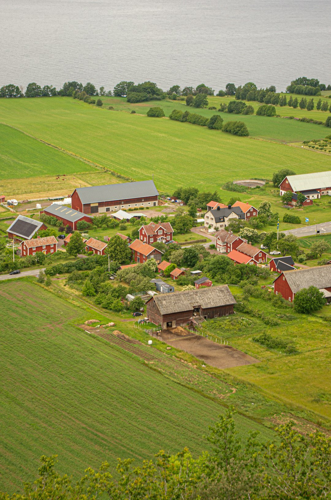 An aerial view of a farm with a body of water in the background