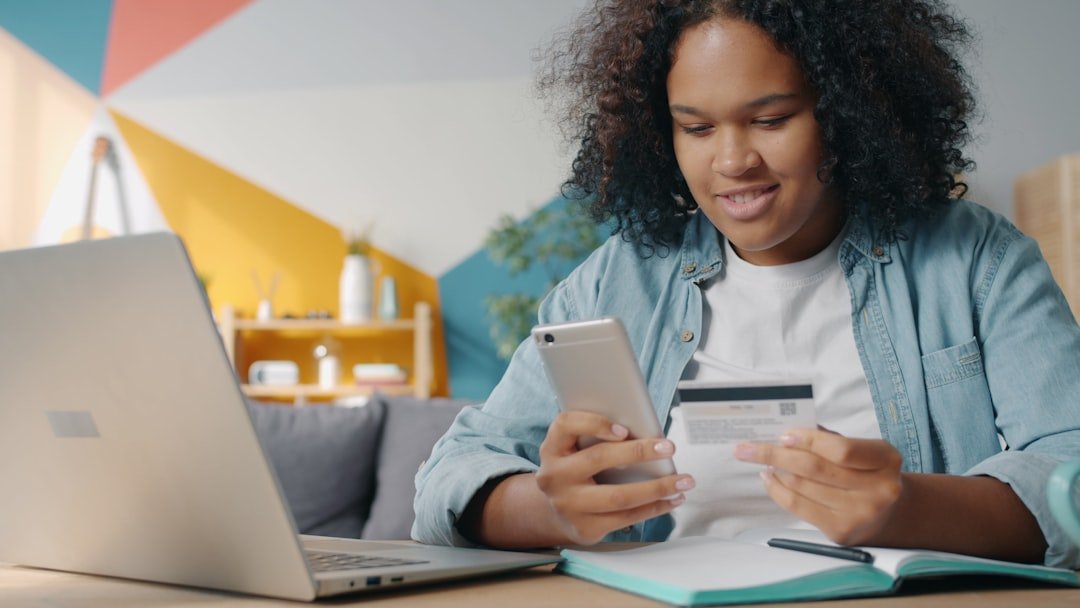 Teenager using phone and credit card for online shopping.