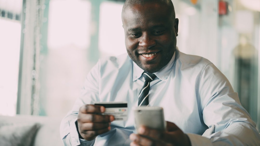 Man smiling while holding credit card and phone