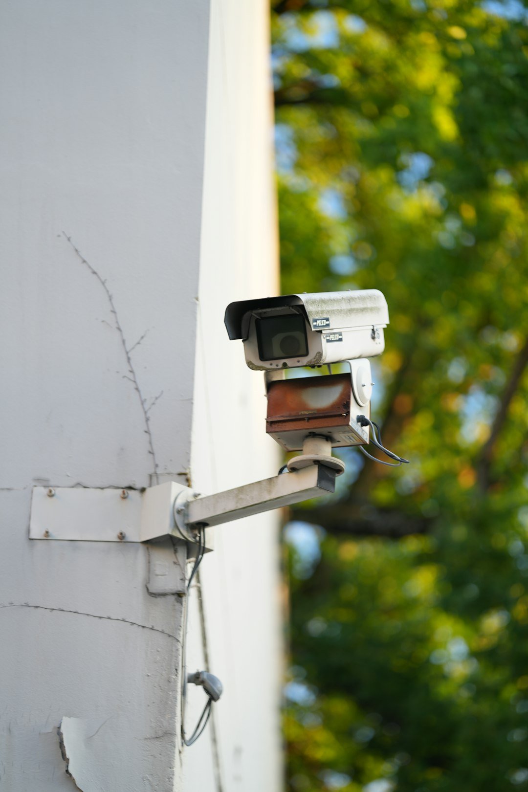 Security camera mounted on a white building wall.