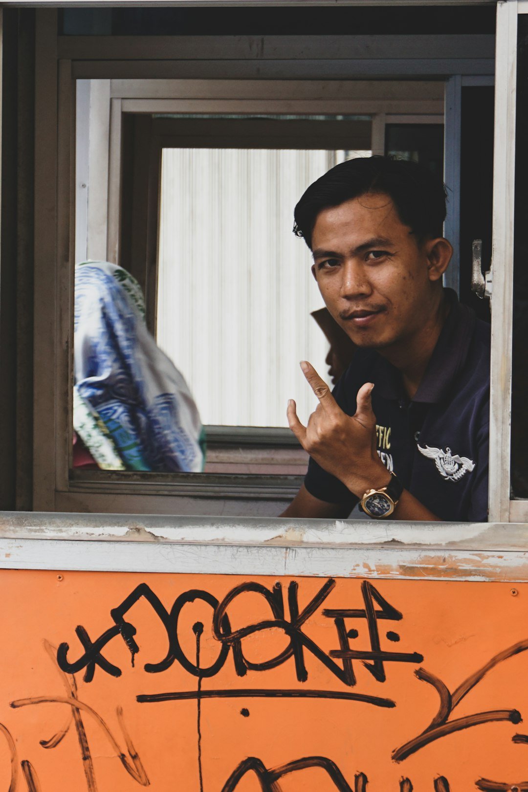 A man is looking out of a window with graffiti on it